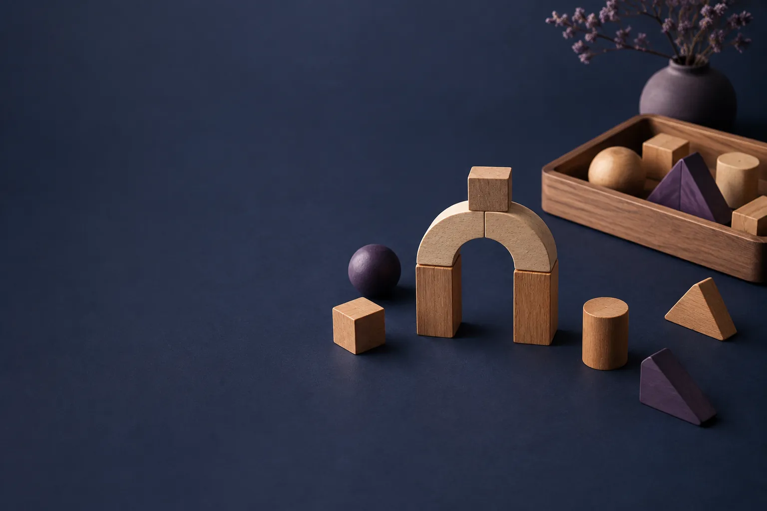 Wooden pieces assembled into an arch beside loose shapes and a tray of spare parts.